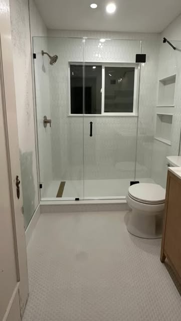 Finished bathroom with a glass shower enclosure and light tile